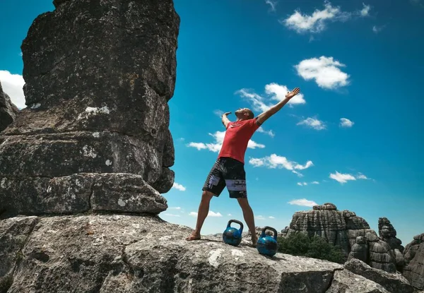 Successful man doing exercises with kettlebells on the mountain, healthy lifestyle, outdoor, training.