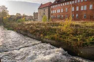 Sonbaharda şehrin içinden akan nehir eski binaların arka planına karşı.