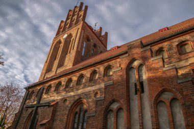 Mavi gökyüzünün arka planında eski kırmızı tuğla kilise ve kulede saat.