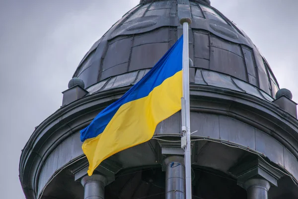 Kubbe ve gökyüzü şeklinde bir çatının arka planında bir bayrak direğinde Ukrayna bayrağı