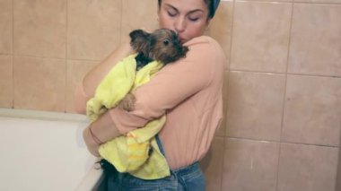 Kadın havluyla köpeği kurutup ısıtıyor.
