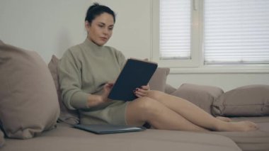 Kadın tablet üzerinde çalışıyor. Belgeyi kontrol ediyor ve yeni bir fikir ediniyor.