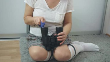 Tanınmayan yüzü olan bir kadın mikrofiber kumaşla dürbün merceği temizliyor.