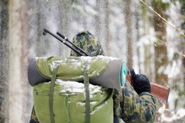 Avcı ya da asker sırtı karla kaplı durur.