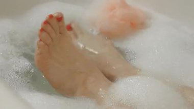 Tanımlanamayan bir yüz küvette dinleniyor bacaklarını hareket ettiriyor, sadece ayak parmakları görünüyor.