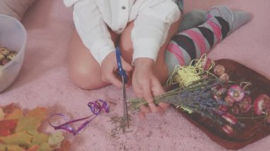 Kuru çiçekleri makasla kesmek için tanınmayan bir yüz, sadece bacaklar ve kollar görünür.