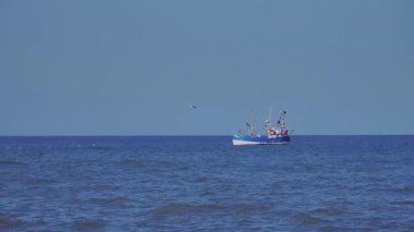 Tanımlanamayan yüzleri olan insanlar, uzaktaki balıkçılar bir balıkçı teknesinde yüzüyor ve ağlarını suya atıyorlar.
