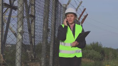 Kask takan sevimli kadın inşaat mühendisi ve belgeyi gerçek hayattaki durumuyla karşılaştırıyor.