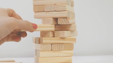 Tanınmayan bir yüzü olan biri istiflenmiş sopalardan bir çubuk çıkarır, sadece kolları görünür.