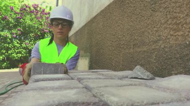 Şirin kadın inşaat işçisi yığınla tuğla yığıyor.