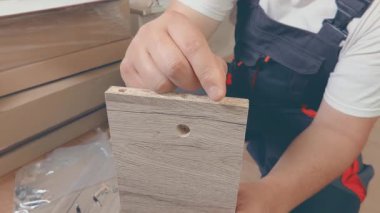 Kapalı, tanınmayan bir yüze sahip mobilya derleyicisi tahta kazıklar, sadece bacaklar ve kollar görünür