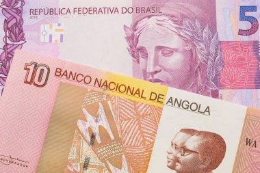 Brezilya 'dan gelen pembe ve mor beş banknotun makro görüntüsü Angola' dan gelen renkli on kwanza banknotuyla eşleştirildi. Makro çekimde yakın çekim.