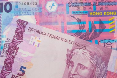 Brezilya 'dan gelen pembe ve mor beş banknotun makro görüntüsü. Hong Kong' dan gelen pembe ve mor bir 10 dolarlık plastik banknotla eşleştirilmiş. Makro çekimde yakın çekim.