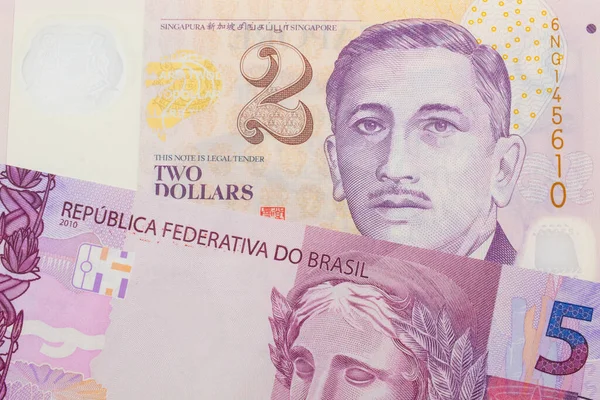 ブラジルのピンクと紫の5つの本物の銀行券のマクロ画像は シンガポールからの紫と白 プラスチックの2ドル札と対になりました マクロでショットを閉じる — ストック写真