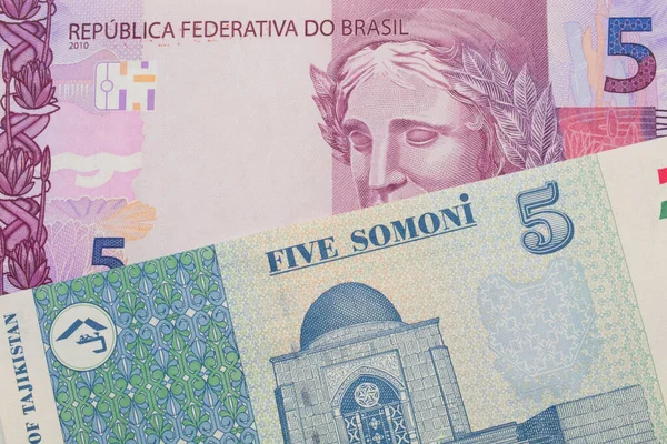 ブラジルのピンクと紫の5つの本物の銀行券のマクロ画像は タジキスタンの青と白の5つのソノニ銀行券と対になりました マクロでショットを閉じる — ストック写真