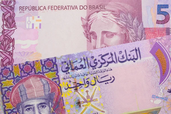 ブラジルのピンクと紫の5本の本物の銀行券のマクロ画像は オマーンのカラフルな1つの紙幣と対になっています マクロでショットを閉じる — ストック写真