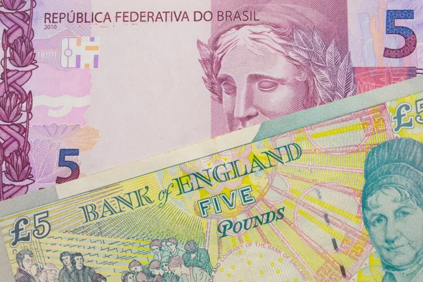 stock image A macro image of a pink and purple five real bank note from Brazil paired up with a colorful, five pound bank note from the United Kingdom.  Shot close up in macro.