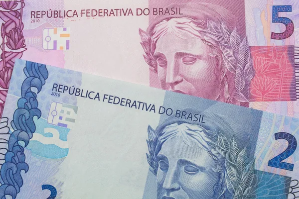 ブラジルのピンクと紫の5つの本物の銀行券のマクロ画像は ブラジルの青い2つの本物の銀行券と対になりました マクロでショットを閉じる ストック写真