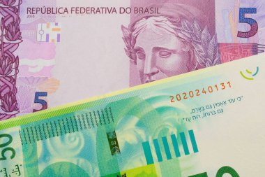 Brezilya 'dan gelen pembe ve mor beş banknotun makro görüntüsü İsrail' den gelen yeşil ve beyaz 50 şekel banknotla eşleştirildi. Makro çekimde yakın çekim.