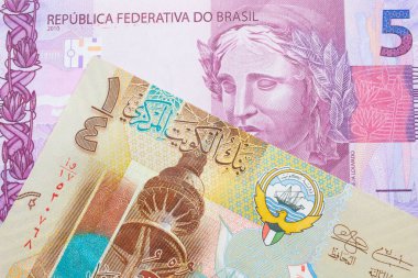 Brezilya 'dan gelen pembe ve mor beş banknotun makro görüntüsü Kuveyt' ten gelen renkli, plastik bir çeyrek dinar ile eşleştirildi. Makro çekimde yakın çekim.