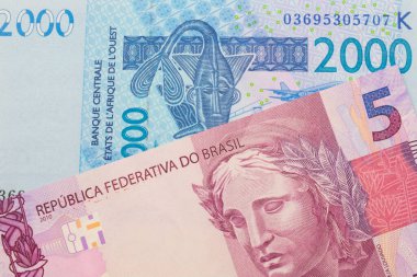 Brezilya 'dan gelen pembe ve mor beş banknotun makro görüntüsü mavi, iki bin Batı Afrika frangı banknotuyla eşleştirildi. Makro çekimde yakın çekim.