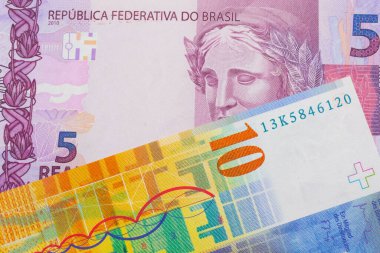 Brezilya 'dan gelen pembe ve mor beş banknotun makro görüntüsü sarı bir İsviçre 10 frangı ile eşleştirildi. Makro çekimde yakın çekim.