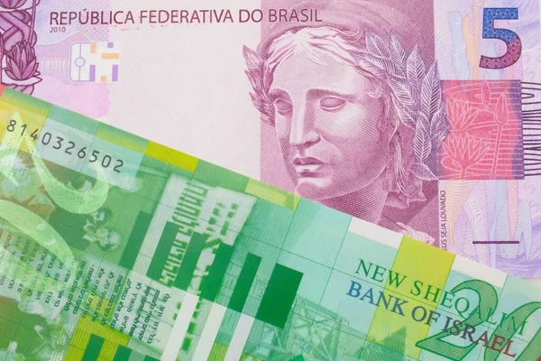 ブラジルのピンクと紫の5つの本物の銀行券のマクロ画像は イスラエルからの緑と白の20のシェケル紙幣と対になりました マクロでショットを閉じる — ストック写真