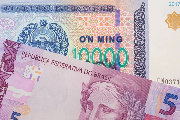 来自巴西的一张粉色和紫色5张真实钞票的宏观图片 与来自乌兹别克斯坦的一张蓝色 白色和绿色1万索姆钞票搭配在一起 在宏观上拍的特写 — 图库照片