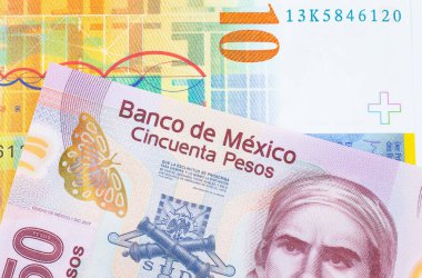 Meksika 'dan gelen 50 pezoluk pembe bir banknotun makro görüntüsü sarı bir İsviçre frangı ile eşleştirildi. Makro çekimde yakın çekim.