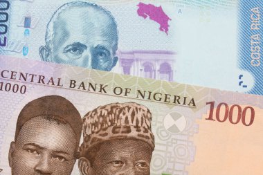 Nijerya 'dan mavi, mor ve yeşil bin nairalık bir banknotun makro görüntüsü Kosta Rika' dan gelen renkli iki bin colon banknotuyla eşleştirildi. Makro çekimde yakın çekim.