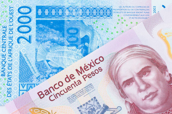 A macro image of a pink, plastic fifty peso bank note from Mexico paired up with a blue, two thousand West African franc bank note.  Shot close up in macro.