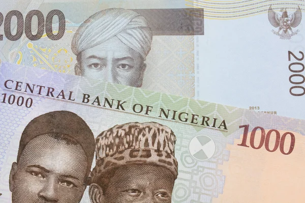 stock image A macro image of a blue, purple and green one thousand  naira note from Nigeria paired up with a grey two thousand rupiah bank note from Indonesia.  Shot close up in macro.