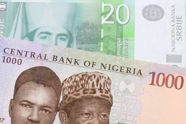 stock image A macro image of a blue, purple and green one thousand  naira note from Nigeria paired up with a green and white twenty dinar banknote from Serbia.  Shot close up in macro.