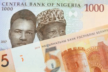 Nijerya 'dan gelen mavi, mor ve yeşil bin nairalık bir banknotun makro görüntüsü Belarus' tan gelen beş ruble turuncu banknotla eşleştirildi. Makro çekimde yakın çekim.