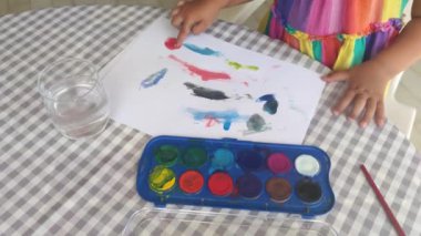 Tanınmayan küçük bir kız parmaklarıyla suluboya yapıyor, yürümeye başlayan çocuklar için eğlenceli aktiviteler, sanat terapisi, yaratıcı boş zaman, ev eğitimi, beceri geliştirme.. 