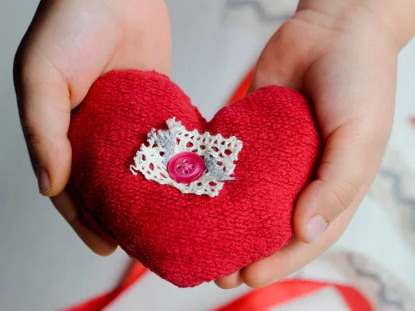 Hand made red heart close up on light background with red ribbon, Valentine day postcard,holiday wallpaper,cover design,needlework hobby,kids hands with heart symbol,copy space
