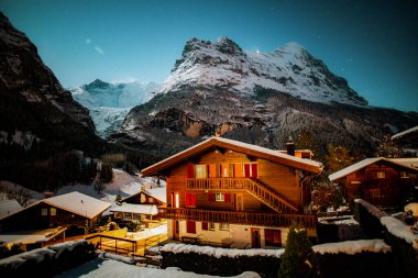 Kış gecesi Grindelwald karlı dağı, yıldızlar ve ahşap ev