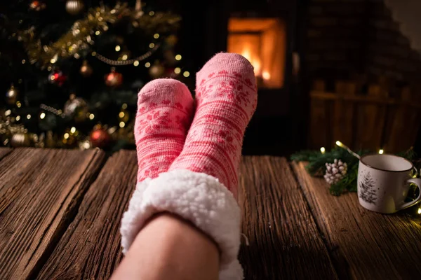 穿着粉色羊毛冬季袜子的女人站在壁炉前 — 图库照片
