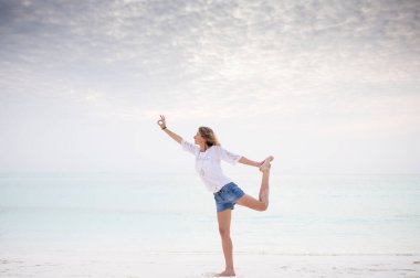 Deniz kenarında yoga yapan kadın. Pastel renkler.