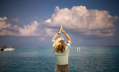 Okyanusun üzerinde günbatımı bulutuna karşı yoga yapan kadın.