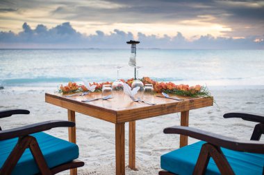 Günbatımı kumsalında romantik yemek masası