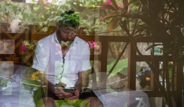 Przystojny Mężczyzna Patrząc Przez Okno Odzwierciedlające Tropikalne Rośliny Zdrowie Psychiczne — Zdjęcie stockowe