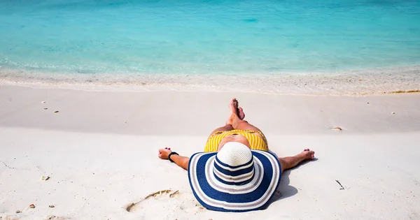 熱帯のビーチでストローハットの日光浴をする女性 — ストック写真