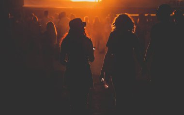 Gün batımı festivalinde yürüyen insanların siluetleri