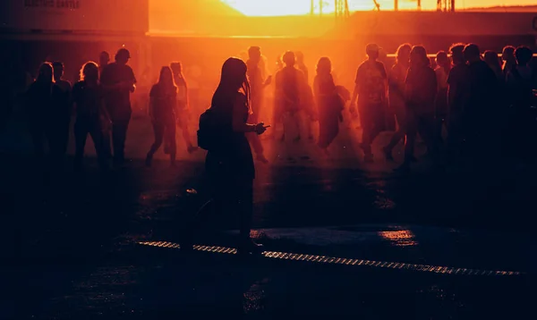 silhouettes of people walking at sunset festival