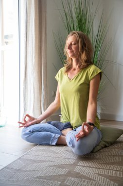 Oturma odasında meditasyon yapan kadın.