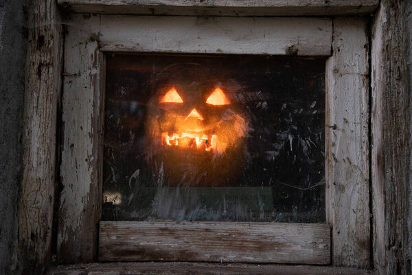 Страшная тыква на Хэллоуин светится в окне ночью