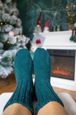 Yün çoraplı kadın şöminenin önünde ısınıyor.