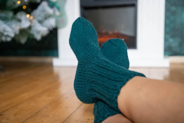 woman in wool socks warming in front of firepalce