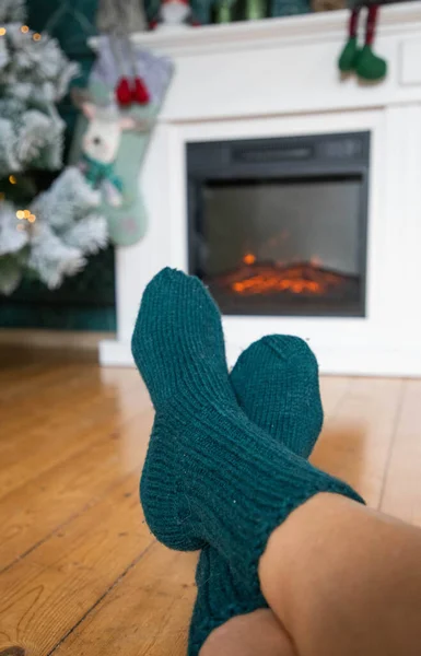 woman in wool socks warming in front of firepalce